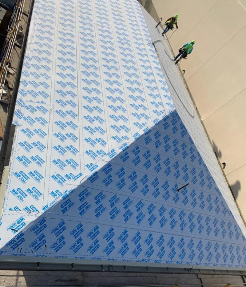 Professional roofers installing underlayment on a metal roof in Plymouth